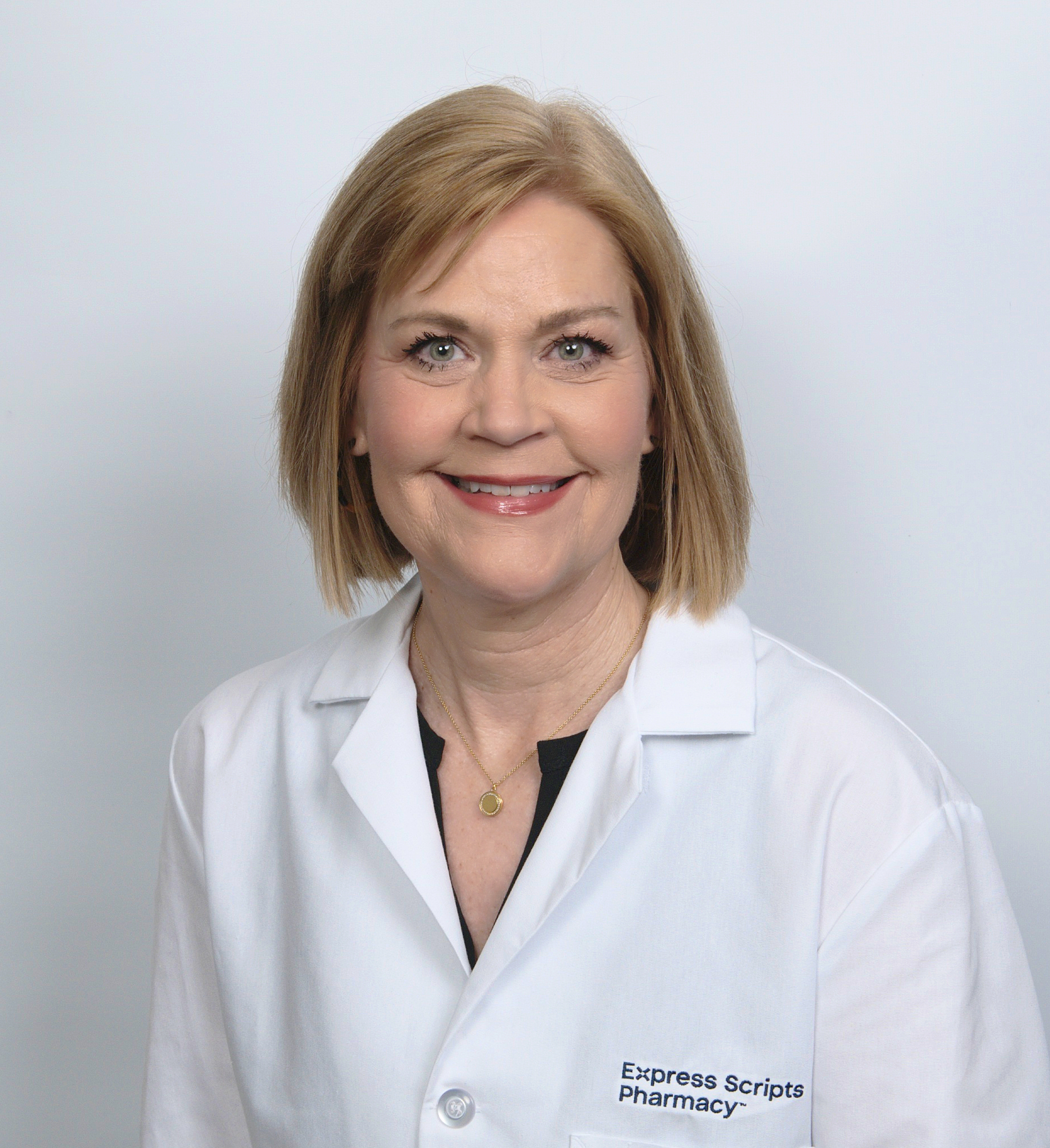 Susan Peppers smiles in her pharmacist lab coat.