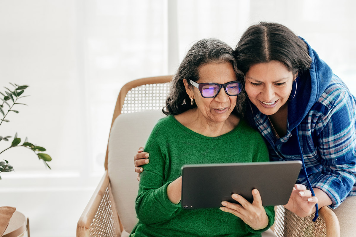 : A young woman and her mother look over a list of her mother’s medications together.