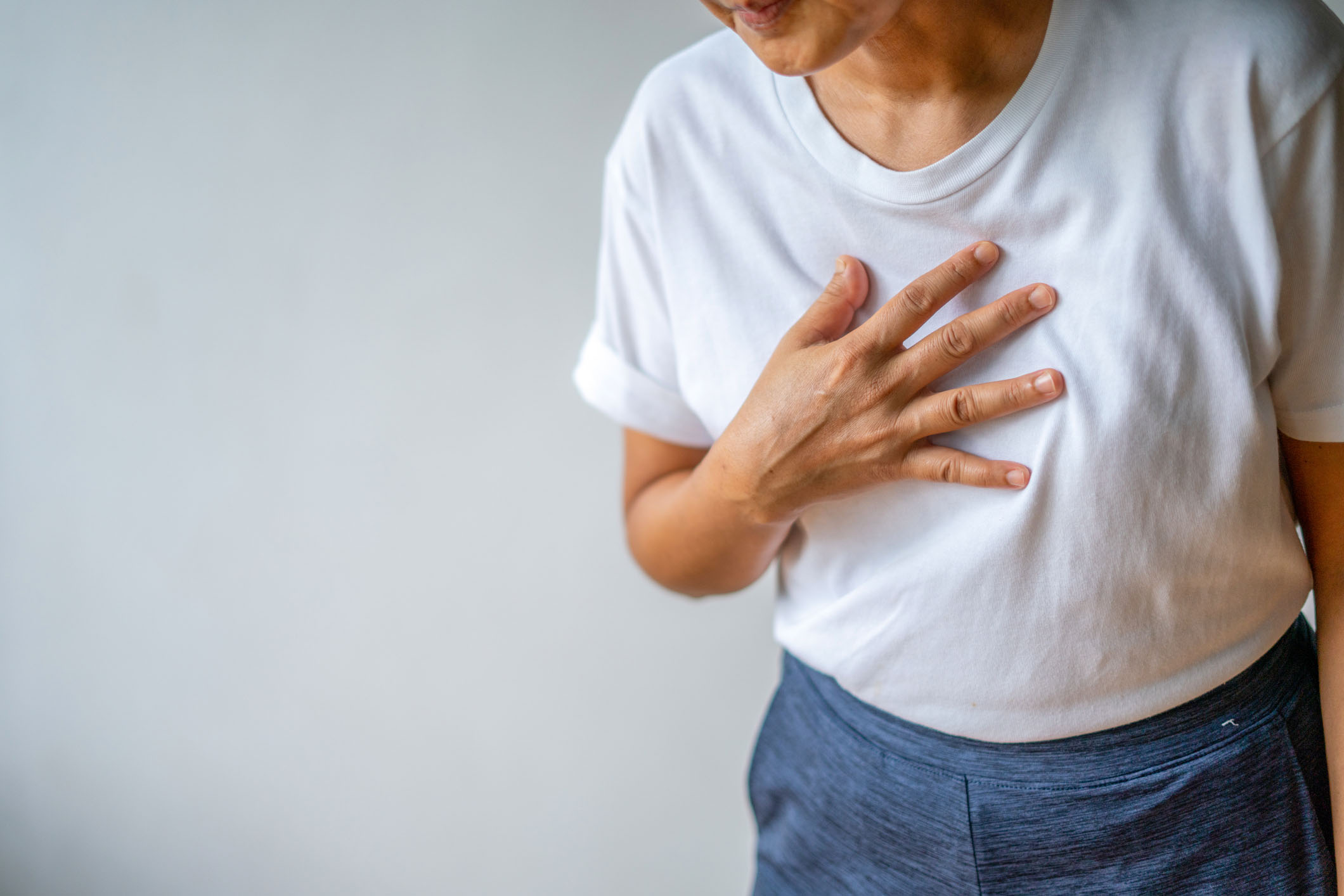 A person experiencing heartburn clutches their chest